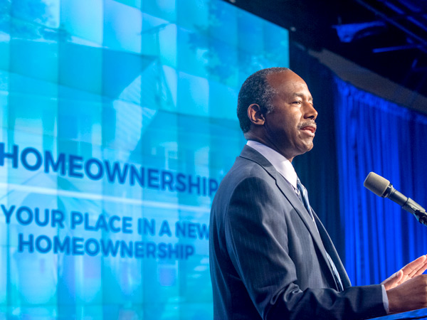 HUD Secretary Ben Carson speaks behind a podium onstage at HUD Headquarters.