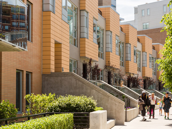 Image of townhouses featuring concrete staircases descending to the street.