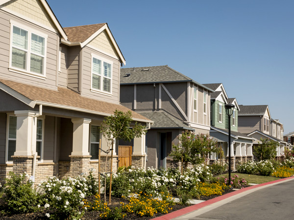 Photograph of two-story single-family houses with front porches and siding facades.