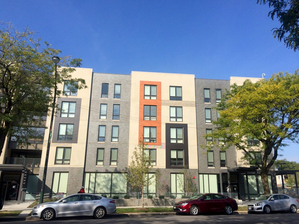 Photograph of a five-story building with residences above ground-floor offices.