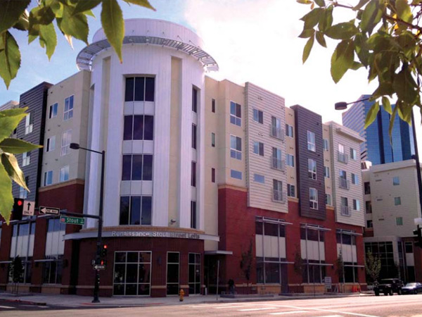 Photograph of the front façade of a five-story building with a health center on the first two floors and apartments on the top three floors.