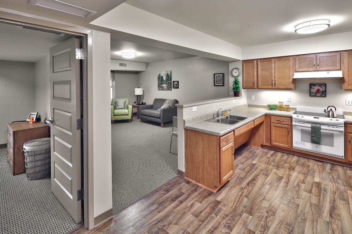 Photograph of the interior of a residential unit with the kitchen separated from the living room by only a half wall.