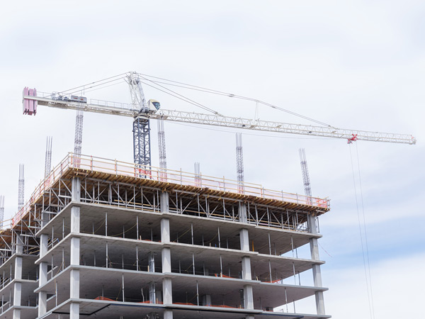 Photograph of a high rise building under construction with a tower crane in the background.