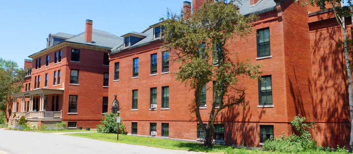 Photograph showing the façade of a low-rise, multi-story brick residential building.