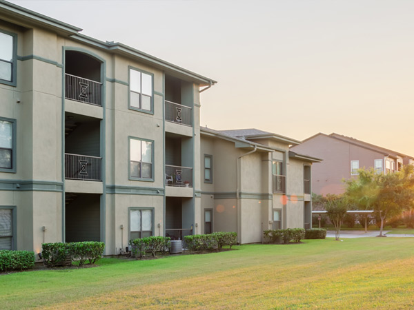 Low-rise garden apartment buildings with porches and balconies adjacent to vegetated open space.