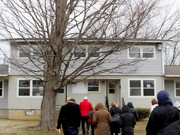 Twelve individuals approach a two-story residential building in Dover, NH. 