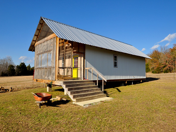 Photograph of a one-story home with a screened-in porch in a field.