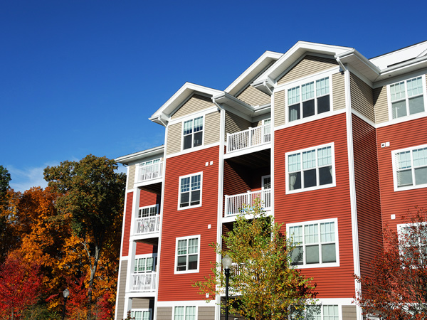 A multistory, garden apartment building surrounded by trees in autumn.