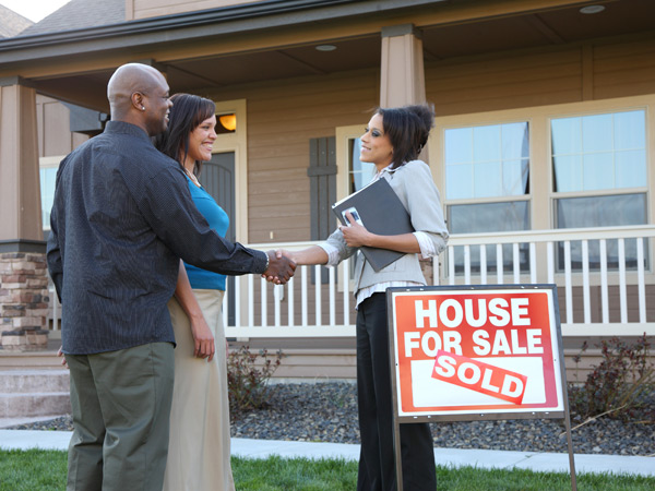 Photo of a couple shaking hands with a realtor outside a new house. Photo of a couple shaking hands with a realtor outside a new house.