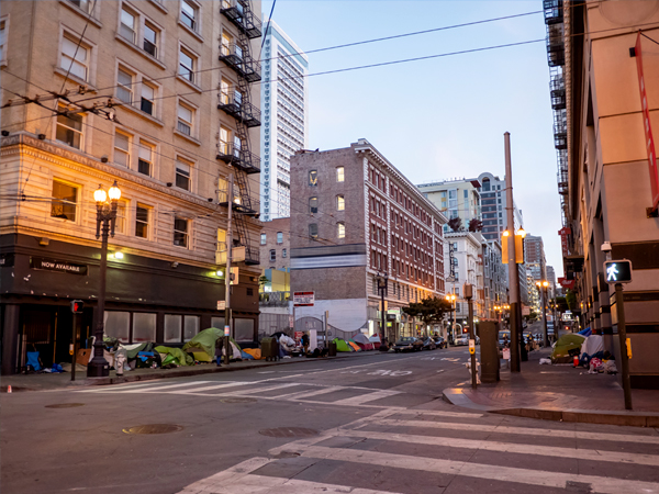 Photo of hotel buildings with tents lined up on the sidewalk.