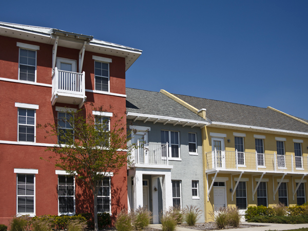 A photo of a housing complex of different colors and sizes under a clear blue sky.