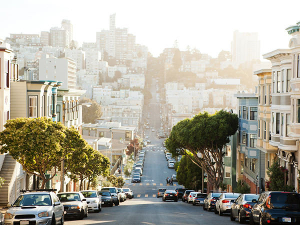 Photograph of a steep San Francisco street lined with buildings and trees.