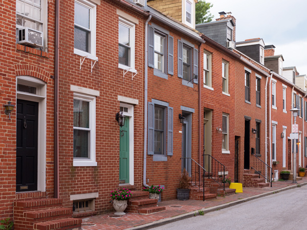 Multistory brick rowhouses line a street.