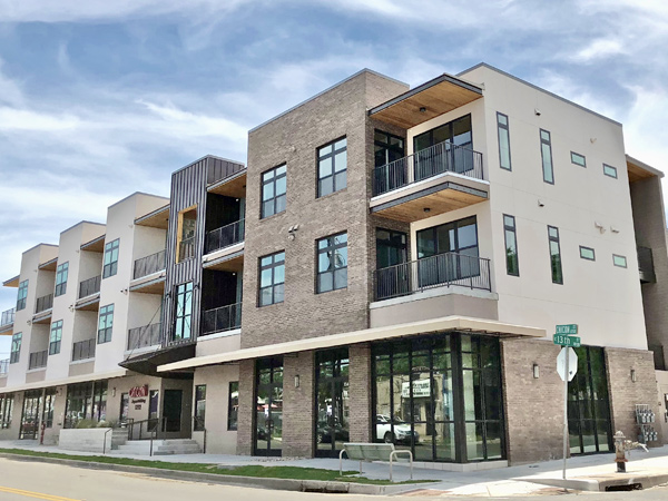 Image of three-story commercial and residential building on a city streetcorner.