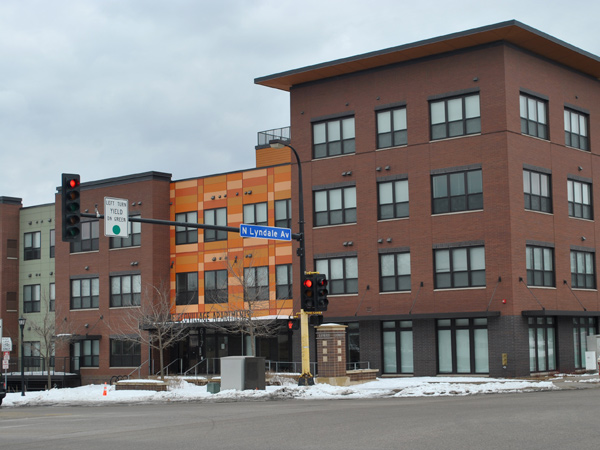 A multi-story apartment building. A stoplight and street sign are visible in the foreground.