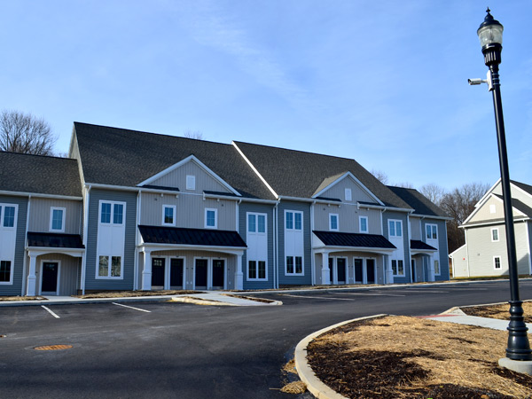 Two multi-story, multifamily residential buildings next to a parking lot.