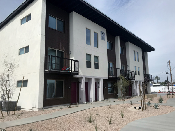 Photograph of a three-story residential building with xeroscaped landscaping.