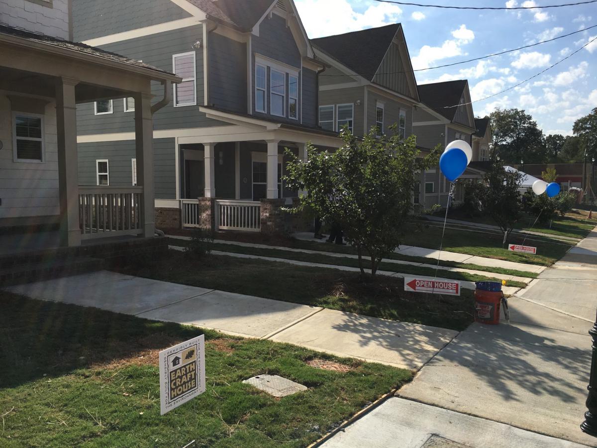 Photo shows a row of single-family homes with walkways in the front yards and a sidewalk.