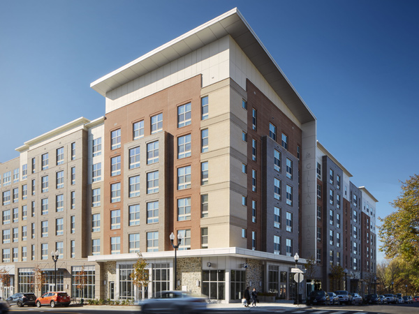 Photograph of a six-story apartment building on a street corner.