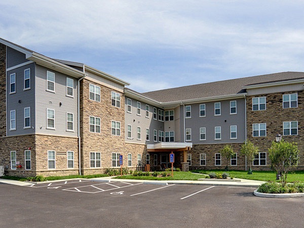 Photograph of an L-shaped, three-story residential building in a contemporary style.