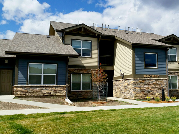 Photograph of a two-story apartment building with grass in the foreground.