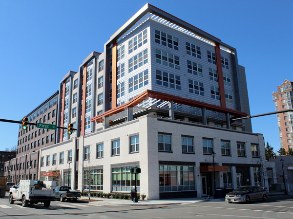 Photograph of the front and side facades of a seven-story building in a contemporary style, with a deep setback at the third floor.