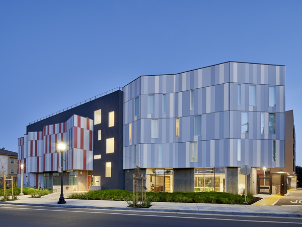 Photograph of a four-story modern apartment building at twilight.