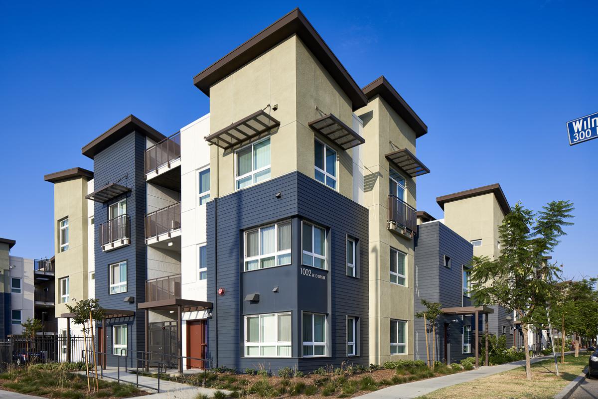 Photograph of the front and side facades of a contemporary three-story building surrounded by sidewalks and landscaping.