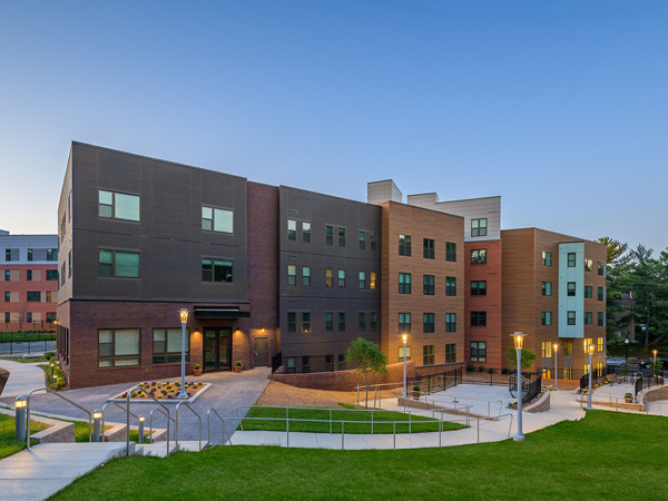 Photograph of a five-story apartment building with surrounding greenspace.