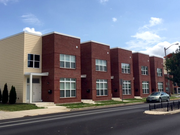 Photograph of a row of five two-story brick townhouses.