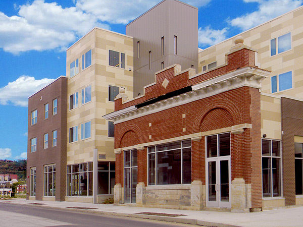 A modern four-story apartment building. Part of the building incorporates an old brick façade of a one-story structure.