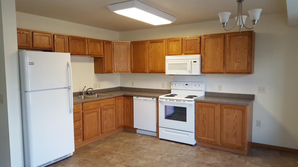 Photograph of a kitchen area with refrigerator, oven, dishwasher, and microwave.