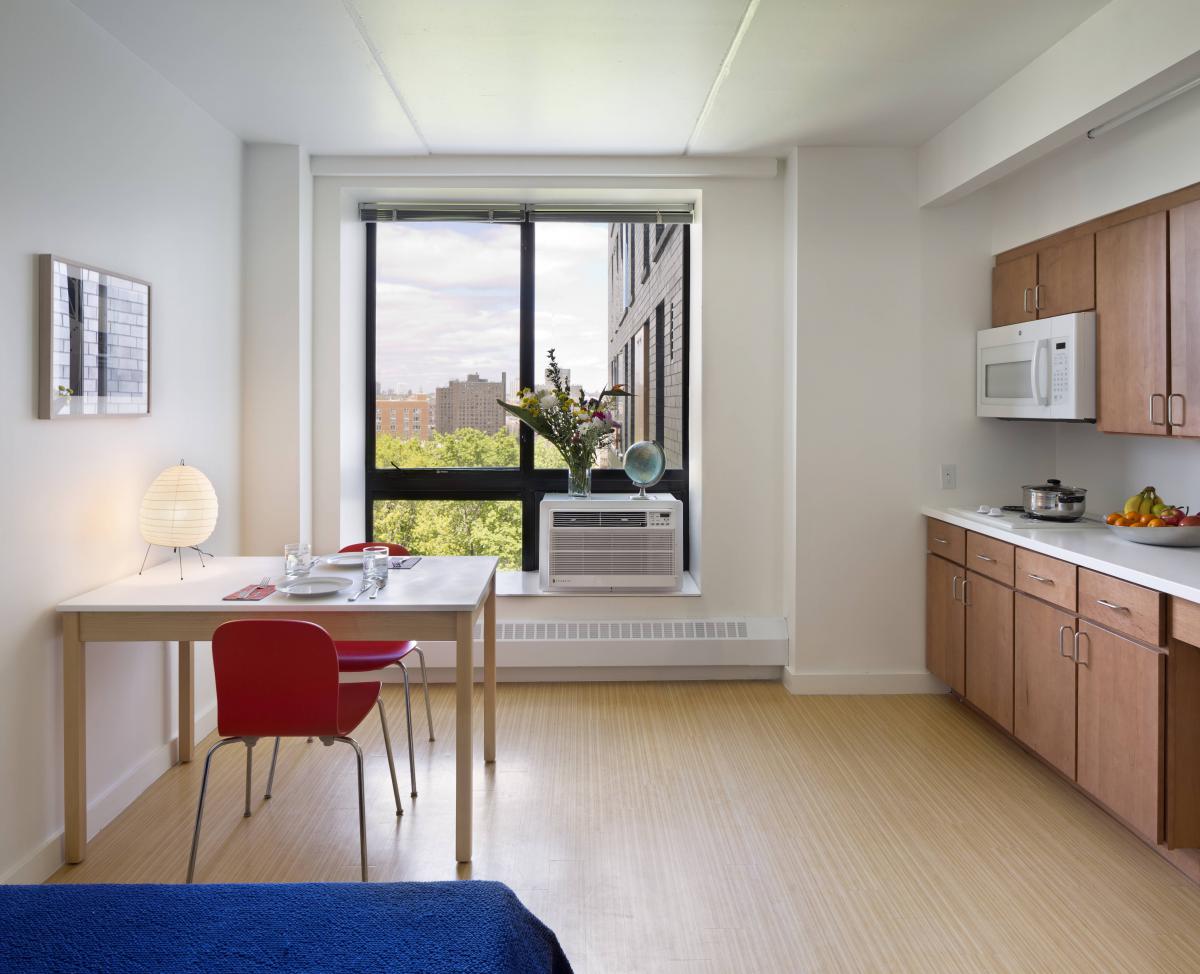 Photograph of a kitchenette area with microwave, countertop hot-plate, table, and chairs.