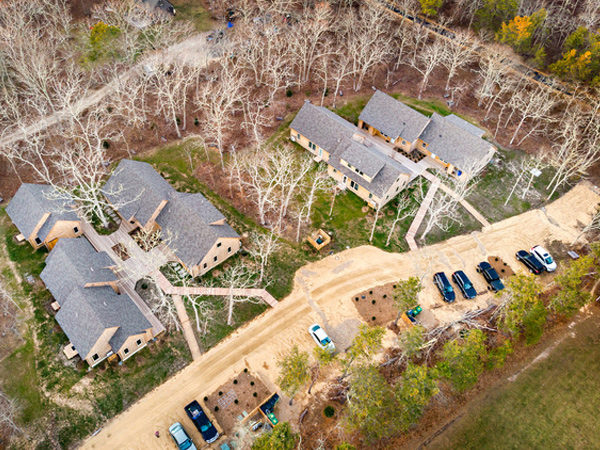 Aerial photograph of two clusters of duplex homes surrounded by trees.