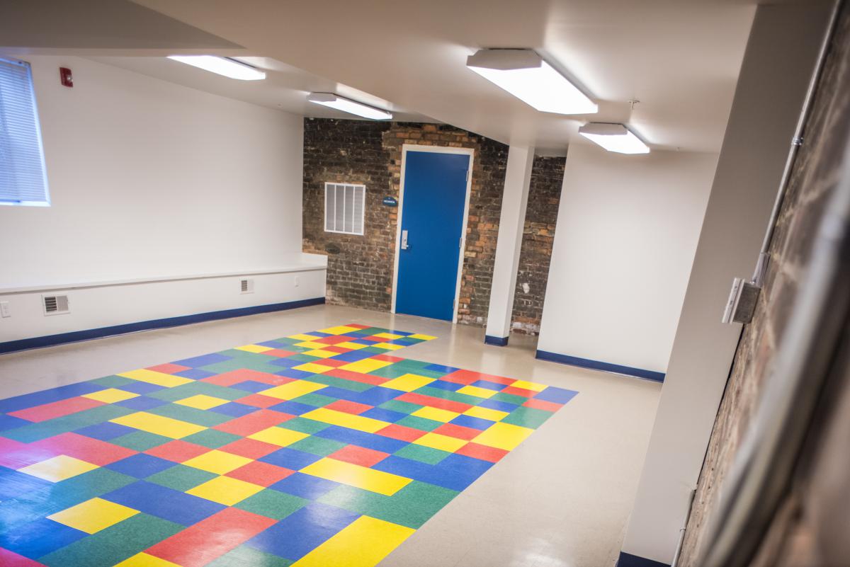 Photograph of a room with drywall and exposed brick walls and a tile floor.