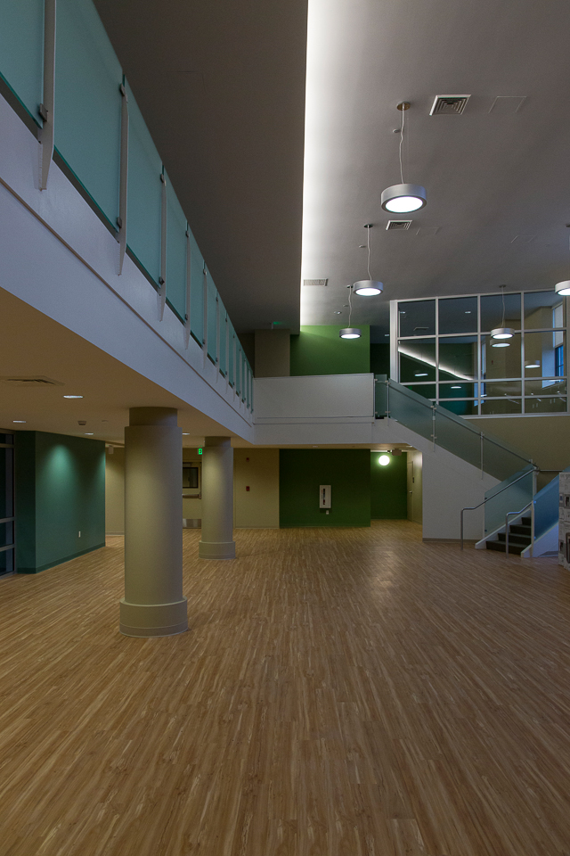 Photograph of a large empty interior space, with wooden floors and a second-floor mezzanine.