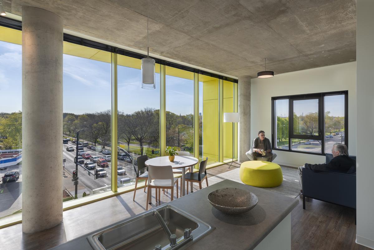 Two people seating in front of large floor to ceiling windows.