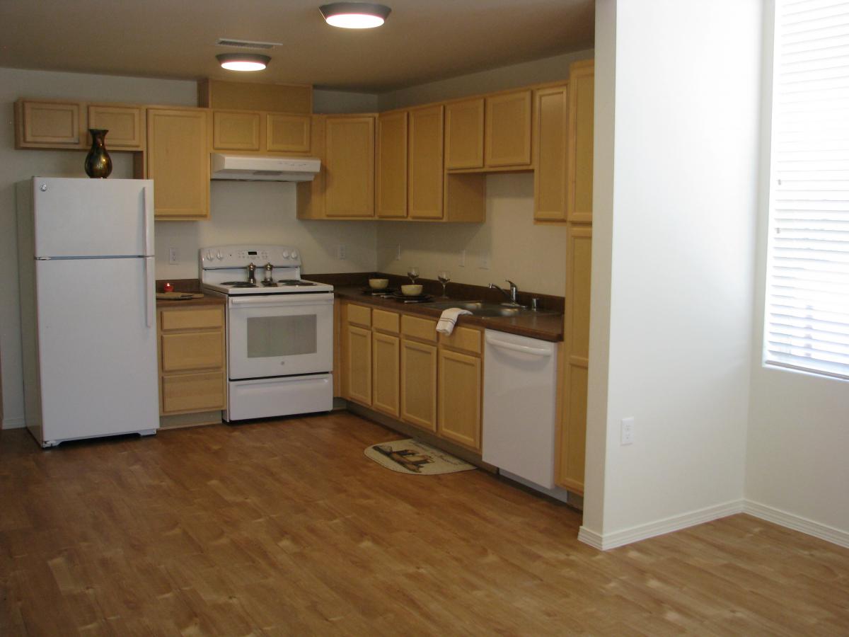 Photograph of a kitchen with wood floors and cabinetry.