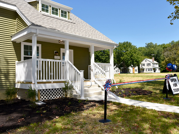 Photograph of a restored single family home with a ribbon strung across its entrance.