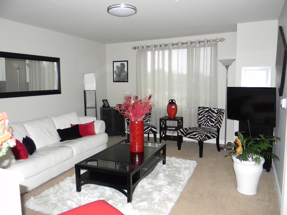 A living room furnished with a sofa, chairs, coffee table, TV stand, TV, mirror and plant. A living room furnished with a sofa, chairs, coffee table, TV stand, TV, mirror and plant.