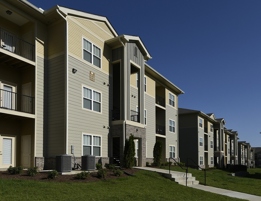 Photograph of the front facades of three three-story apartment buildings.