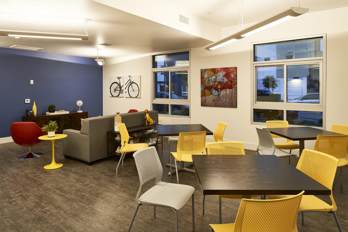 Photograph of a colorful, brightly-lit room with tables, seating, and wall art.