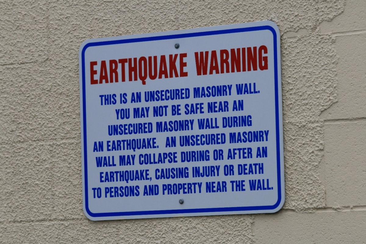 A sign board affixed to a wall showing an earthquake warning.