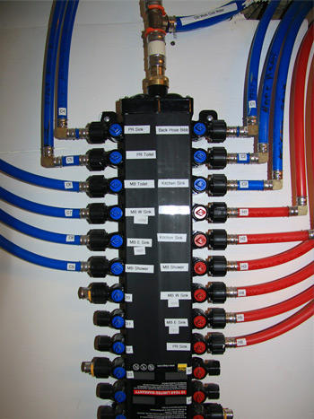 Photograph of a plumbing manifold with individual shutoffs for each water-consuming appliance.