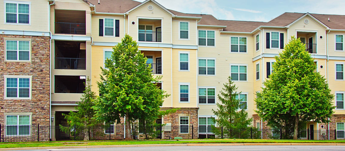 Photograph of a four-story multifamily building with a mixed stone and siding facade.