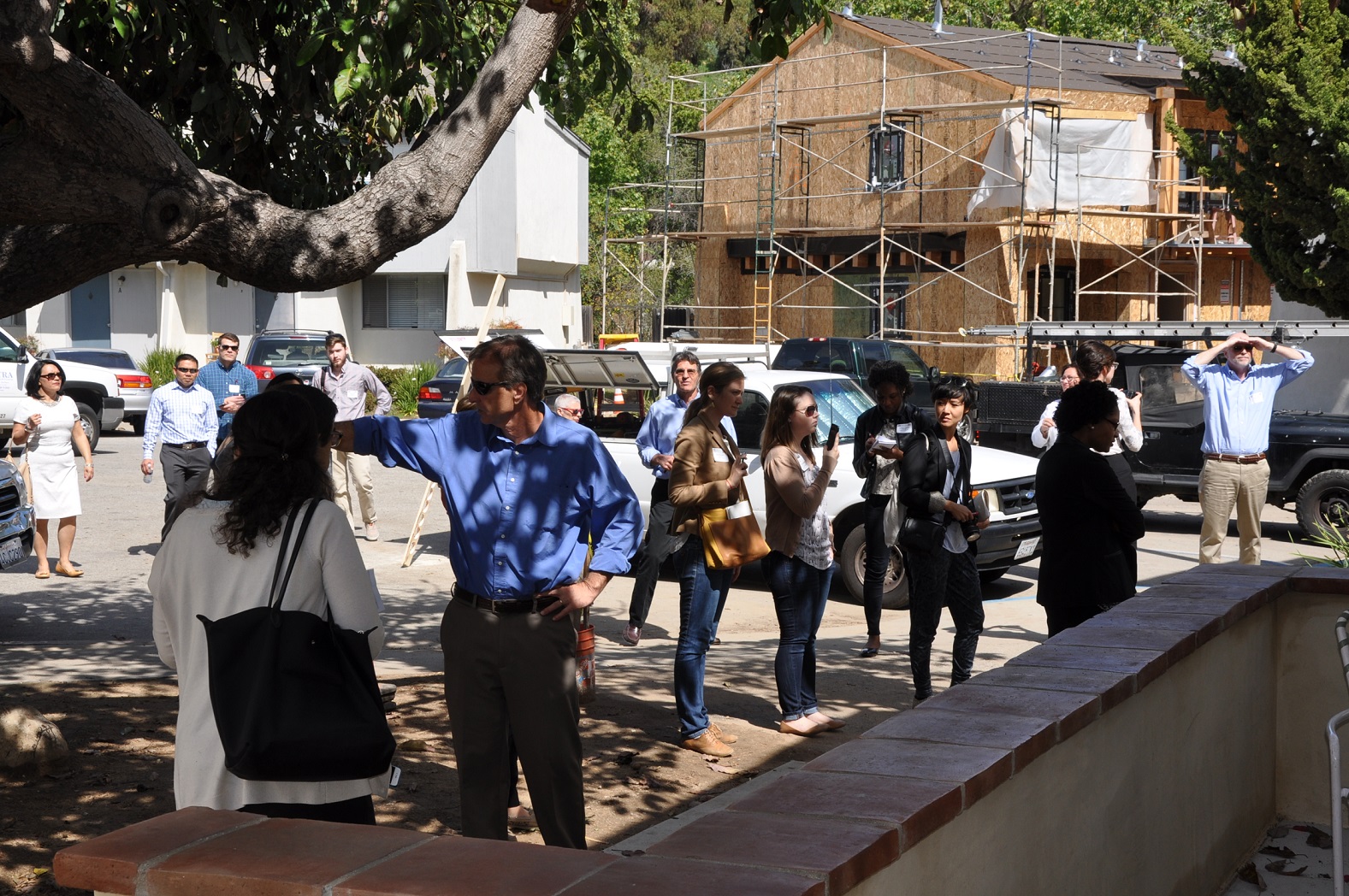 The finalist teams walk around the Monteria Village development site. Two multistory buildings are visible in the background; scaffolding is visible on building on the right.