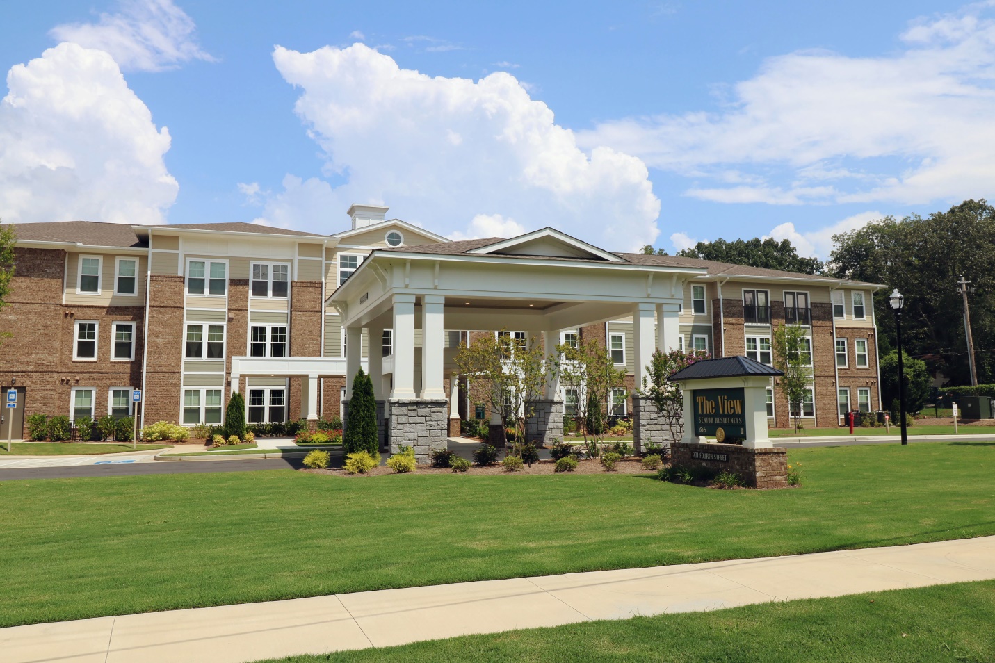 Photograph of the front of a three-story, brick building with a grass lawn in the foreground.