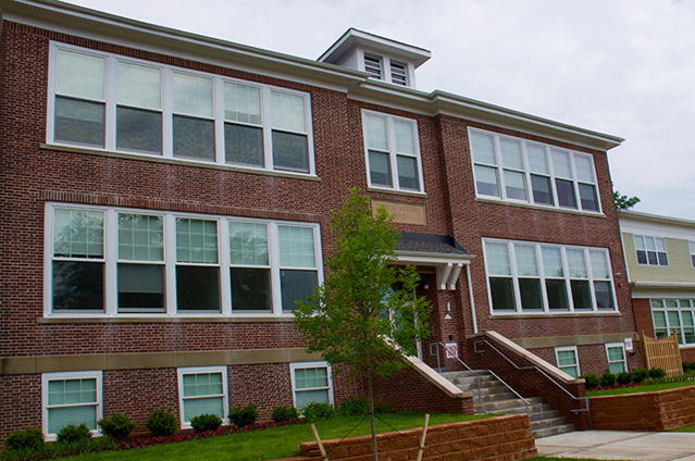 Photograph of the front façade of a three-story brick school building, with a two-story wing at the right edge of the photograph.