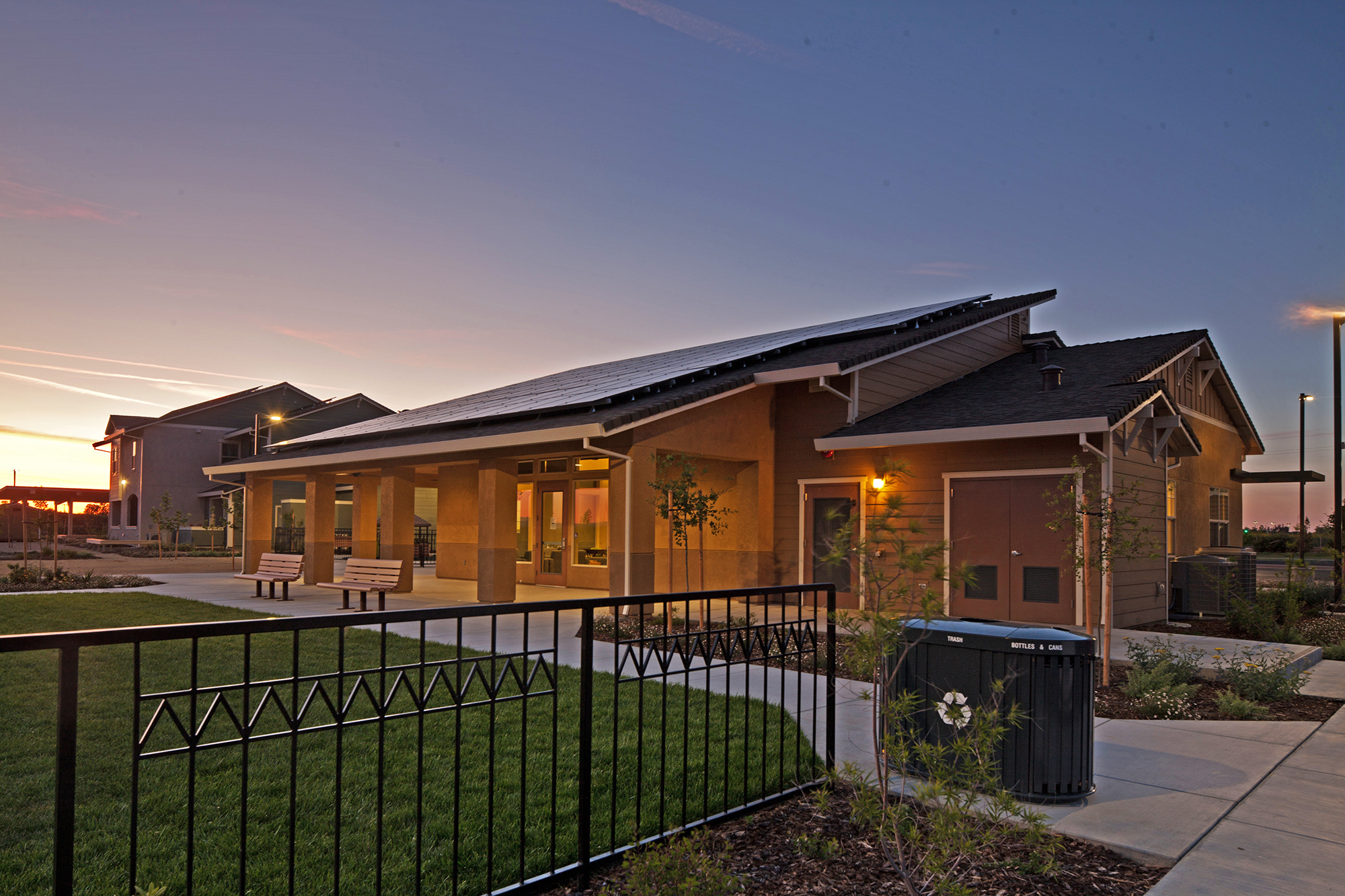 Photograph of the front façade of a one-story nonresidential building with green space in the foreground and a residential building in the background.