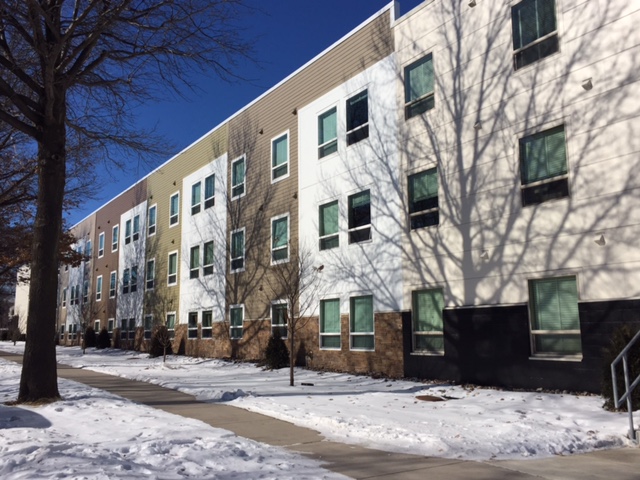 Photograph of a three-story multifamily building extending most of the length of the block.